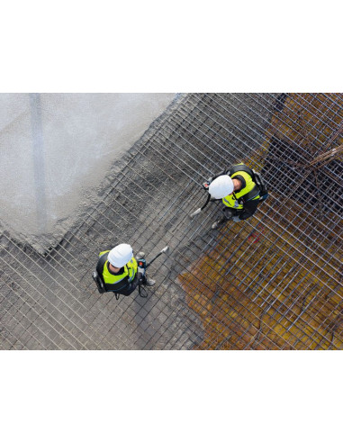 Dva delavca v varnostni opremi uporabljata vibrator za beton na armaturni mreži.